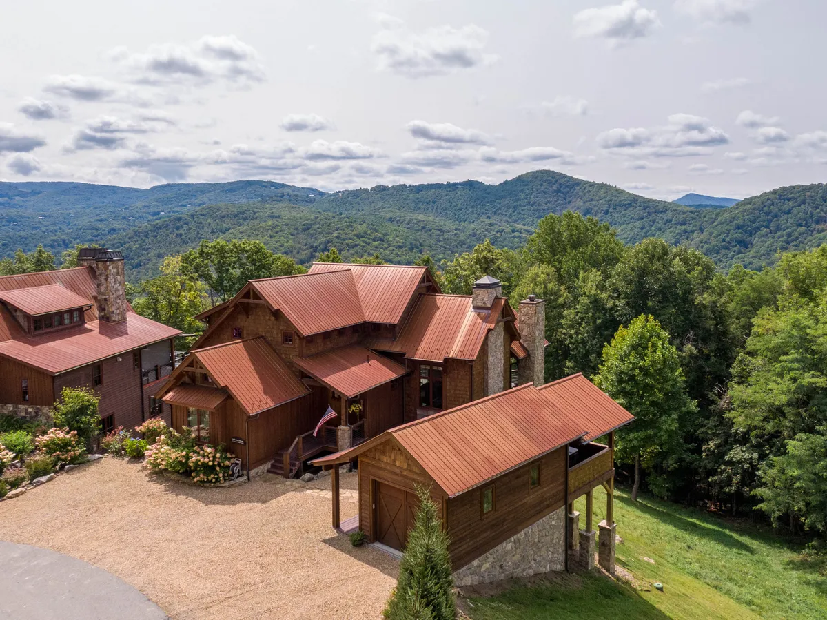 This exterior shot features rustic wooden architecture and bright red metal roofs surrounded by lush mountains and a landscaped garden. The setting evokes a sense of mountain adventure and family togetherness in a serene natural setting, ideal for active and leisurely outdoor experiences.