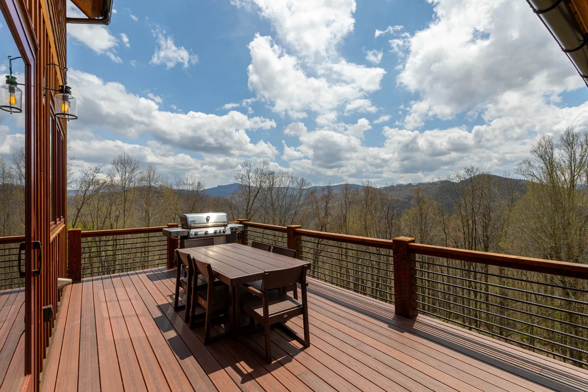 An inviting exterior space with an outdoor dining table and barbecue grill, overlooking sweeping mountain views. The setting offers a tranquil escape for alfresco dining, relaxing with local wines, and taking in breathtaking sunsets with companions.