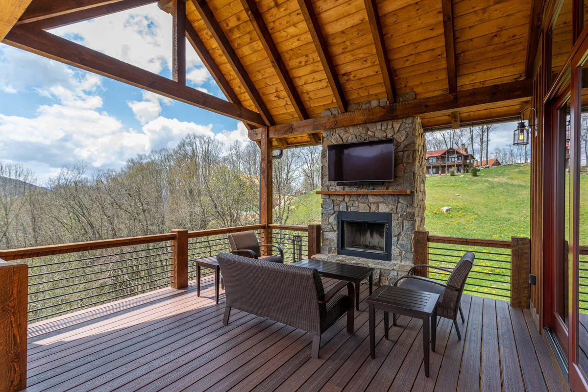An outdoor seating area anchored by a beautiful stone fireplace, with plush sectional seating and sweeping mountain views in the background. The setup is ideal for cozy fireside chats or watching a sunset together, emphasizing comfort and connection with nature.