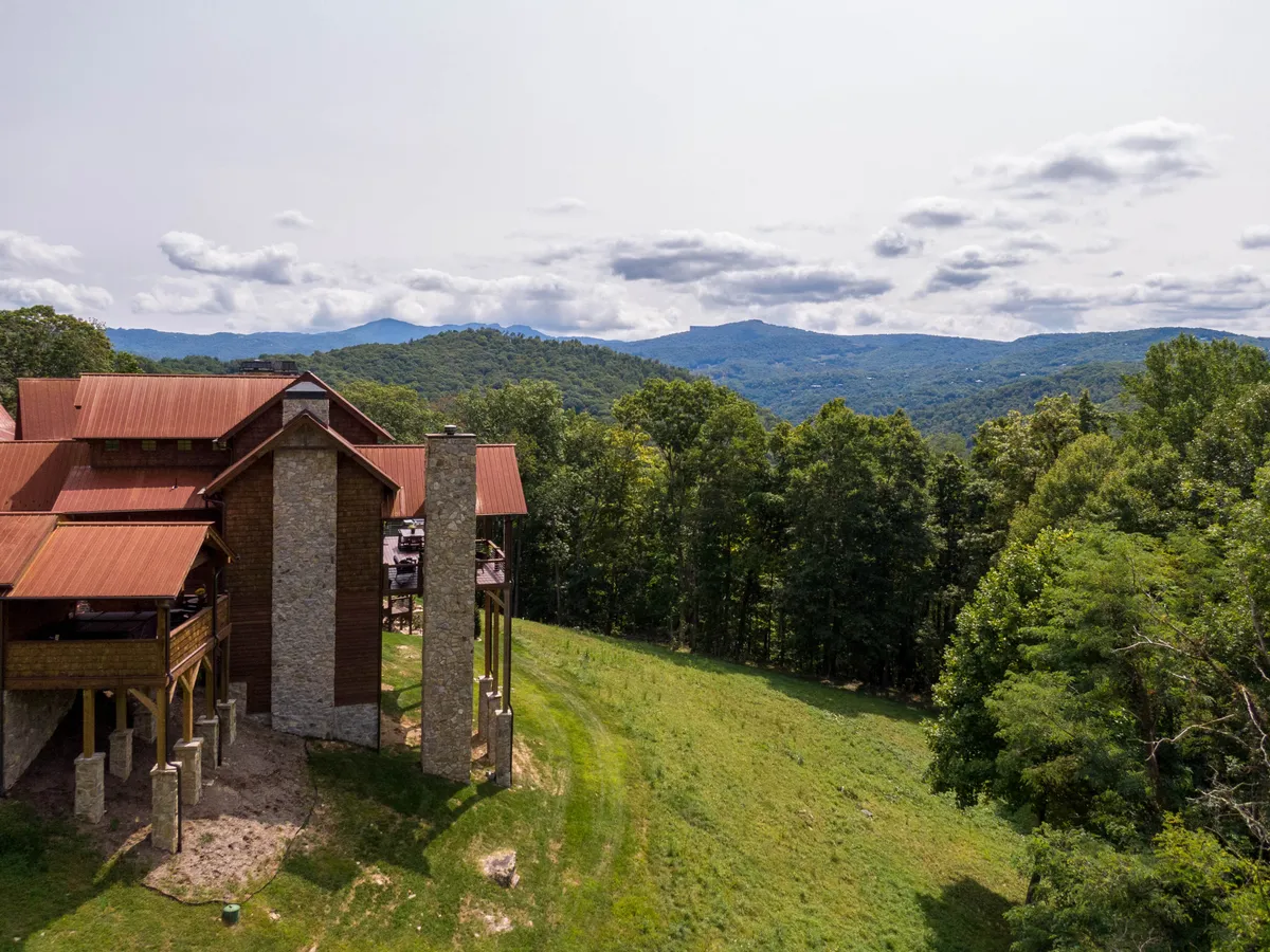 A modern cabin exterior nestled against a backdrop of majestic mountains and lush greenery, with hints of outdoor recreation and space for exploration. This scene captures the essence of Eagles Nest as both upscale and immersed in the natural environment.